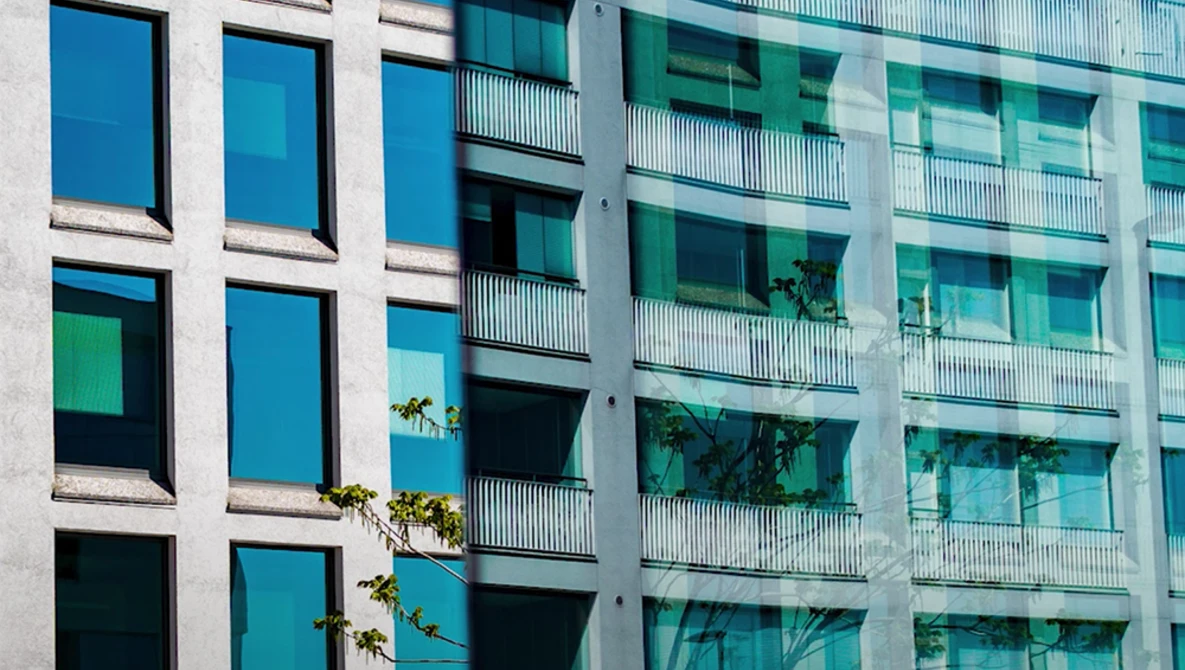 Modern residential building facade with contrasting blue and teal windows arranged in a grid pattern, separated by white concrete columns.