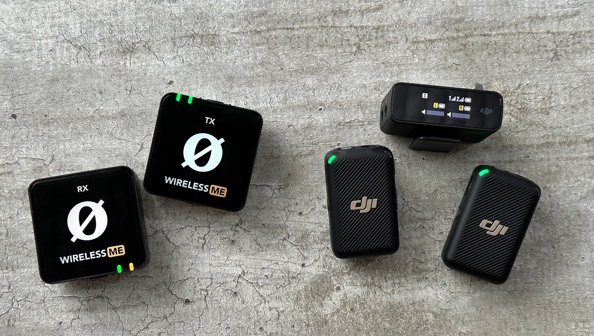 Five wireless microphone transmitter and receiver units arranged on a concrete surface.