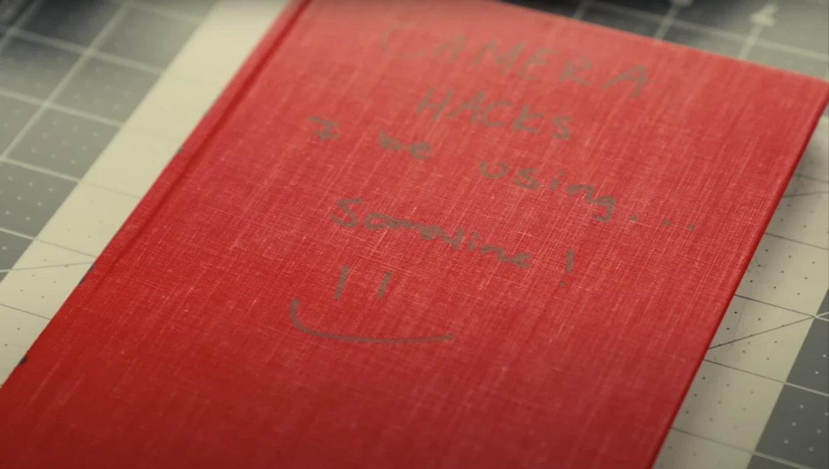 Red hardcover book with embossed text on cover, photographed at an angle on a gridded surface.