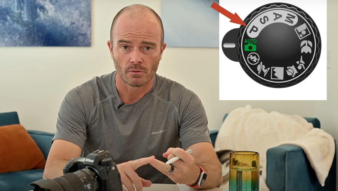 Photographer holding a camera body while examining a vintage lens with an aperture ring detail highlighted.