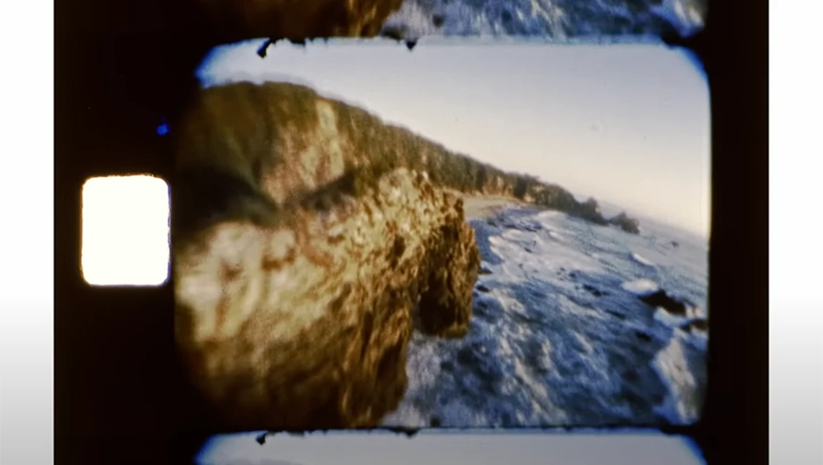 Vintage film camera viewfinder showing snowy mountain landscape with rocky terrain.