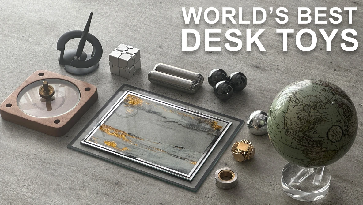 Collection of desk toys arranged on gray surface, including a spinning top, Rubik's cube, compass, magnetic balls, and antique globe.