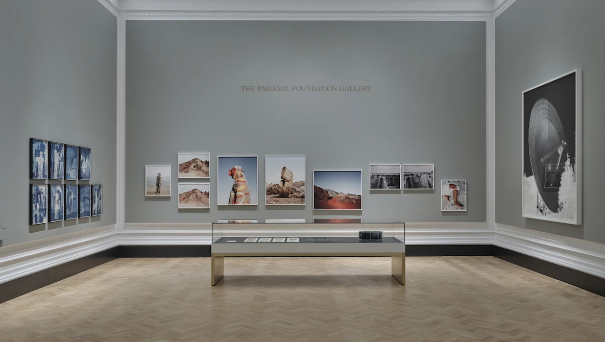 Gallery wall displaying framed photographs of varying sizes arranged symmetrically around a central display case.