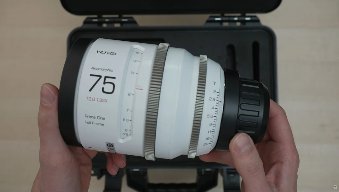 Hands holding a Viltrox 75mm f/1.2 lens with white barrel and focus ring, displayed in black carrying case.
