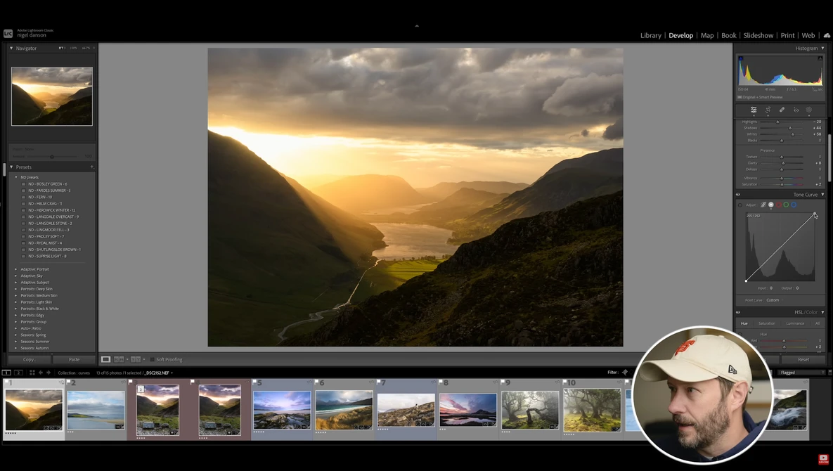 Mountain valley landscape with golden sunset light breaking through clouds over a lake and forested slopes.