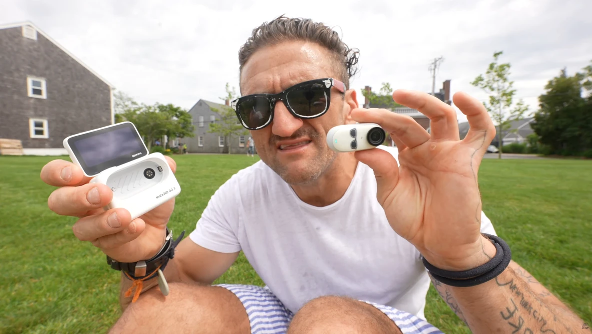 Man holding two compact cameras outdoors, displaying them toward the camera.