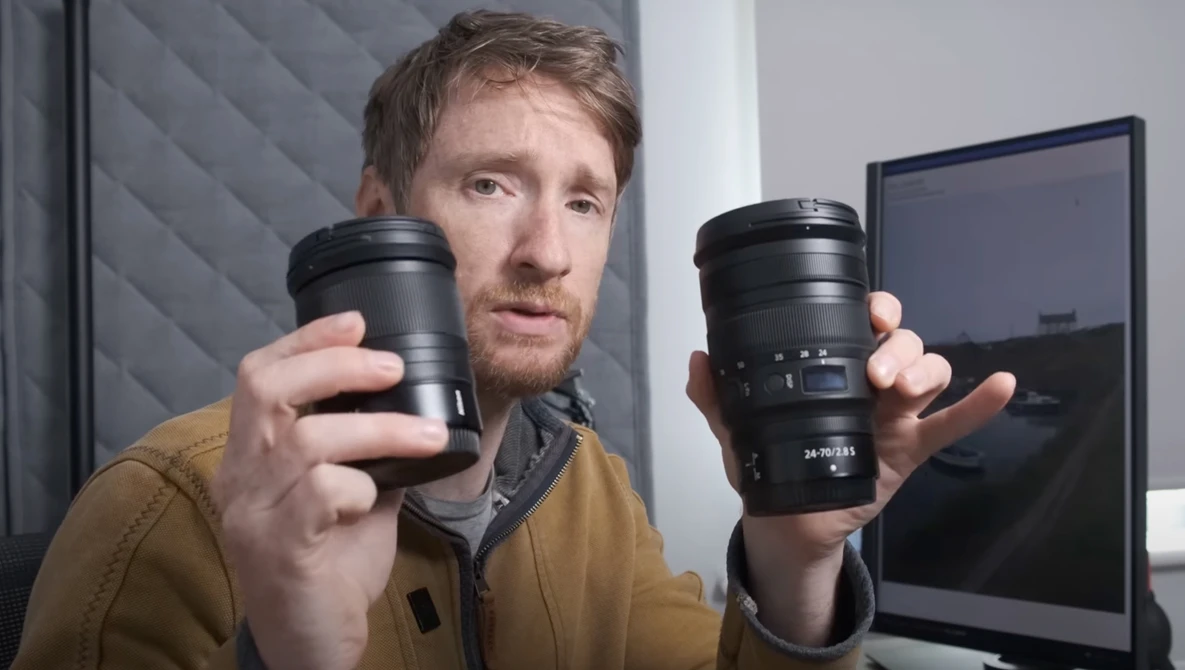 Photographer holding two camera lenses side by side for comparison.