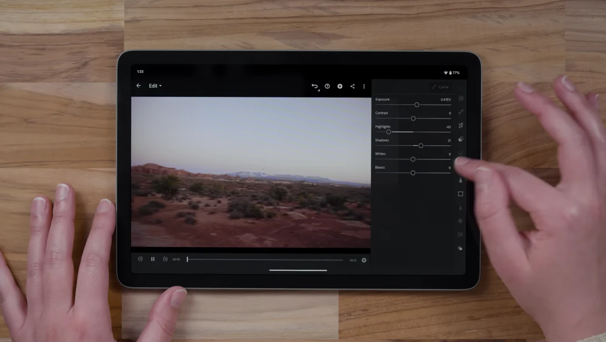 Tablet displaying desert landscape photo in editing software with adjustment panels visible on right side.