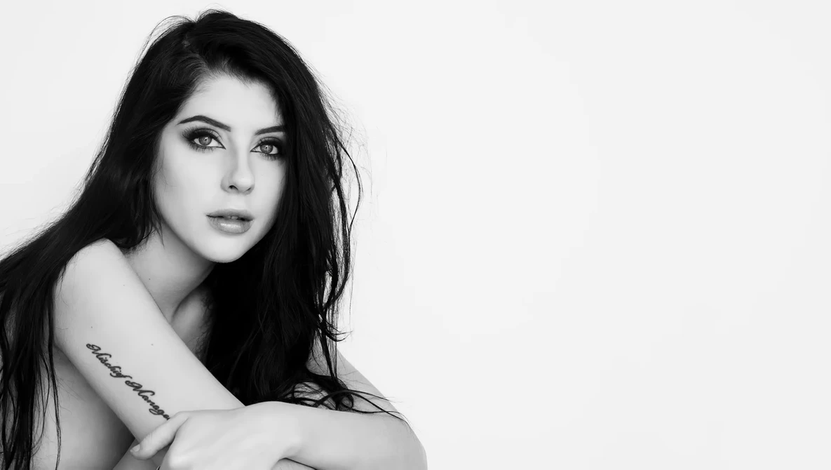 Black and white portrait of a woman with long dark hair, looking over her shoulder with a subtle expression.