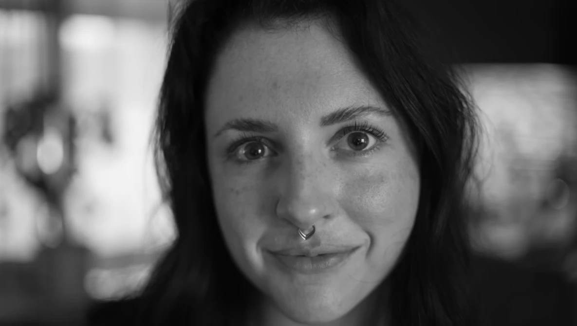 Black and white portrait of a woman with dark hair and a nose ring, slight smile directed at camera.