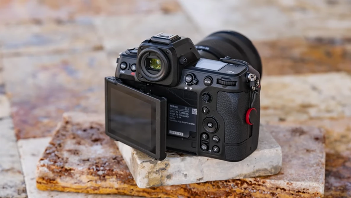 Professional mirrorless camera displayed on a weathered concrete block, showing rear LCD screen and control layout.