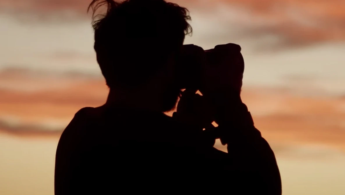 Silhouetted figure holding a child against a golden sunset sky.