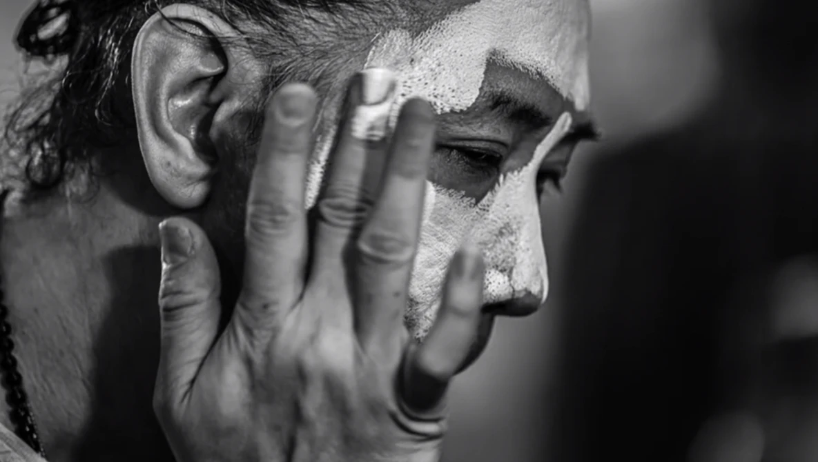 Man's face in profile with hand covering part of his face, shot in black and white.