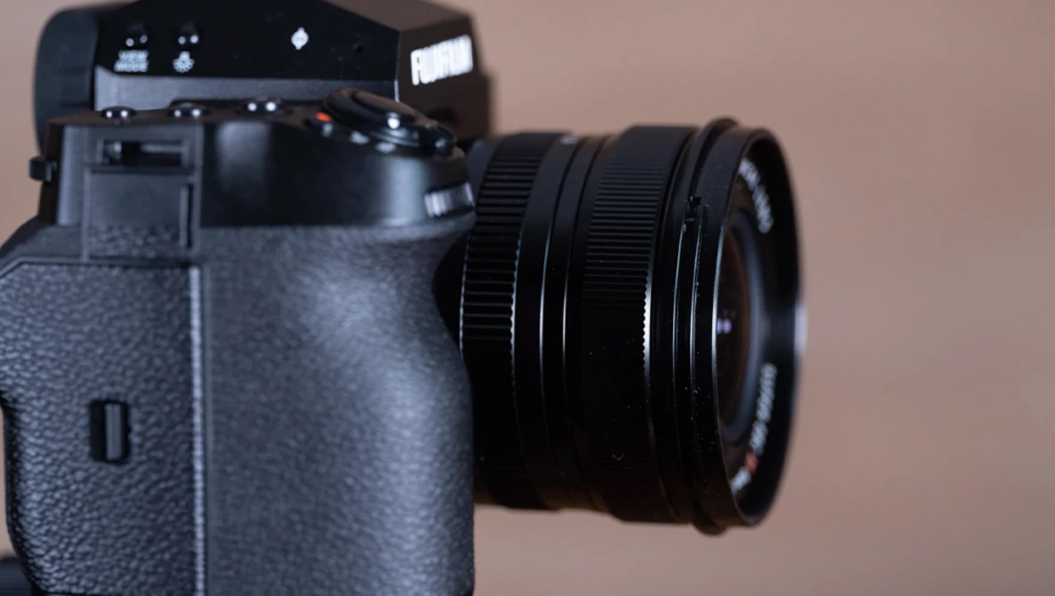 Mirrorless camera with attached zoom lens against a neutral beige background.