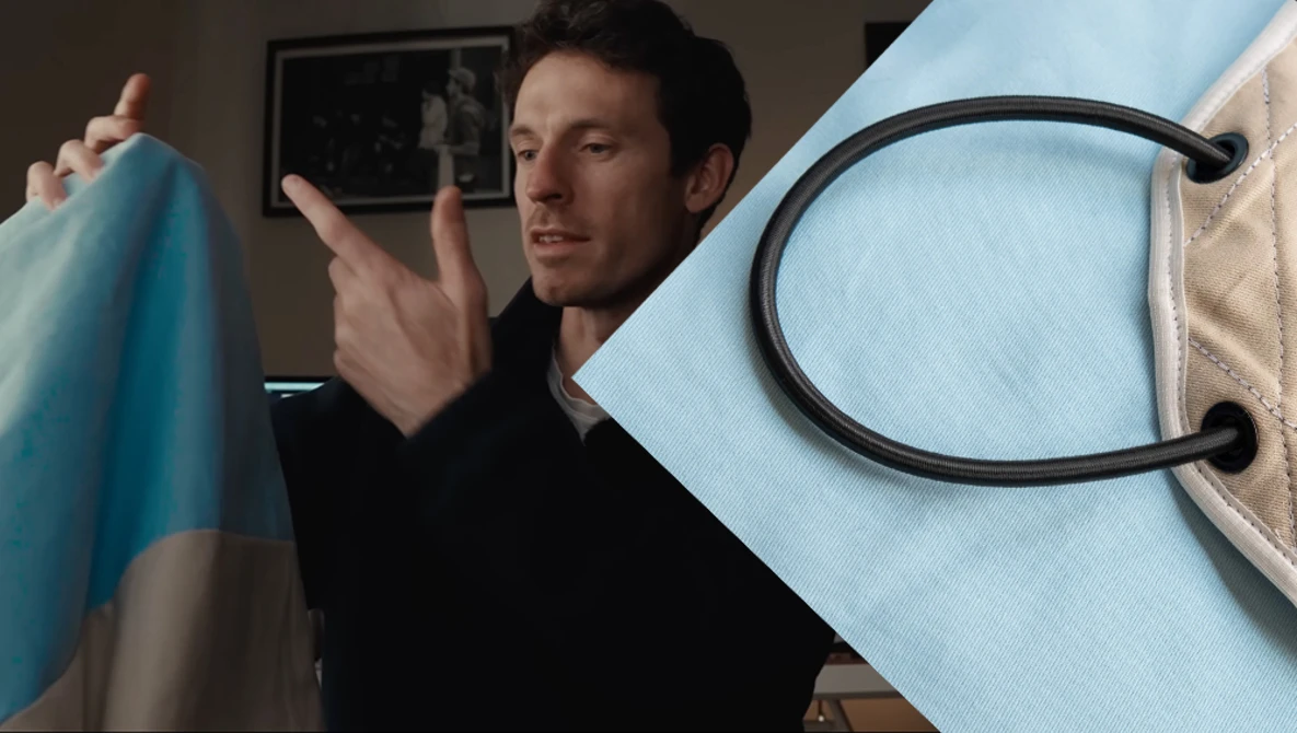 Man in black shirt holding blue fabric while examining it indoors.