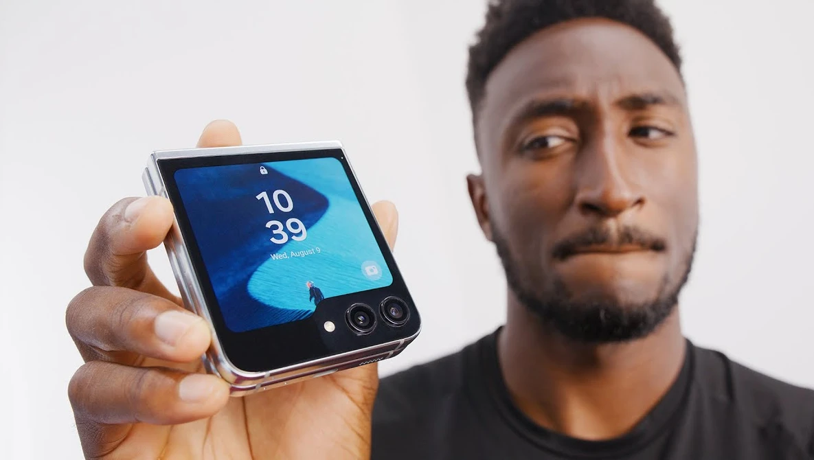 Person holding a foldable smartphone displaying the time 10:39 against a light background.