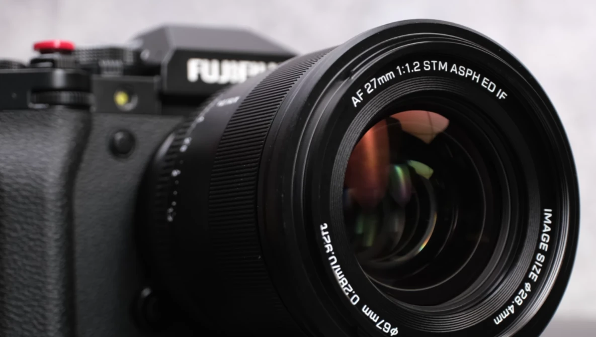 Fujifilm mirrorless camera with a 57mm f/1.2 STM ASPH lens mounted, shot against a snowy background.
