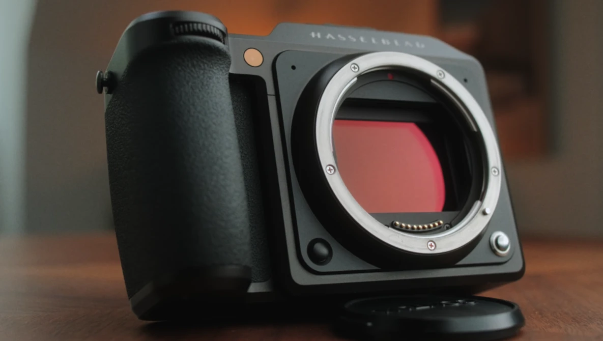 Hasselblad medium format camera with open mirror box and pink sensor filter visible.