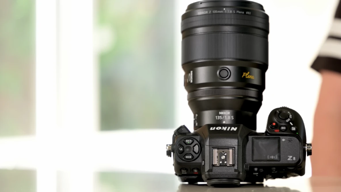 Nikon Z mirrorless camera with attached telephoto lens mounted on white surface.
