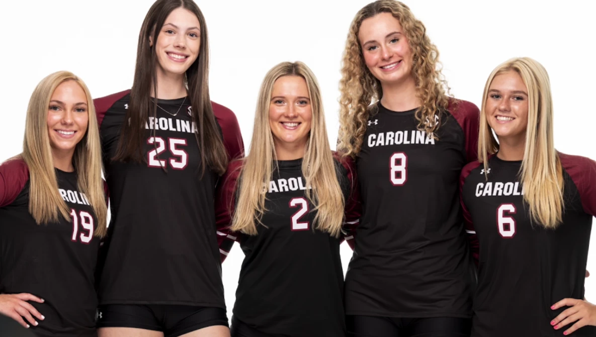 Five volleyball players in black uniforms with Carolina branding posed together for a team portrait.