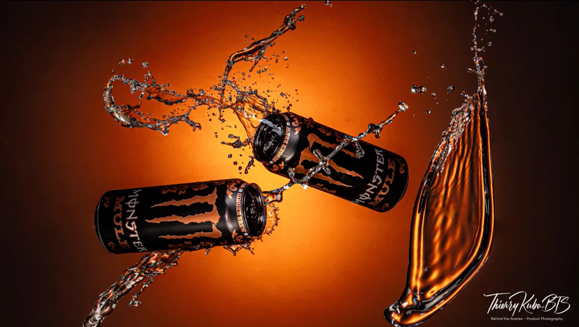 Two beverage cans colliding mid-air with dynamic water splash against warm orange background.
