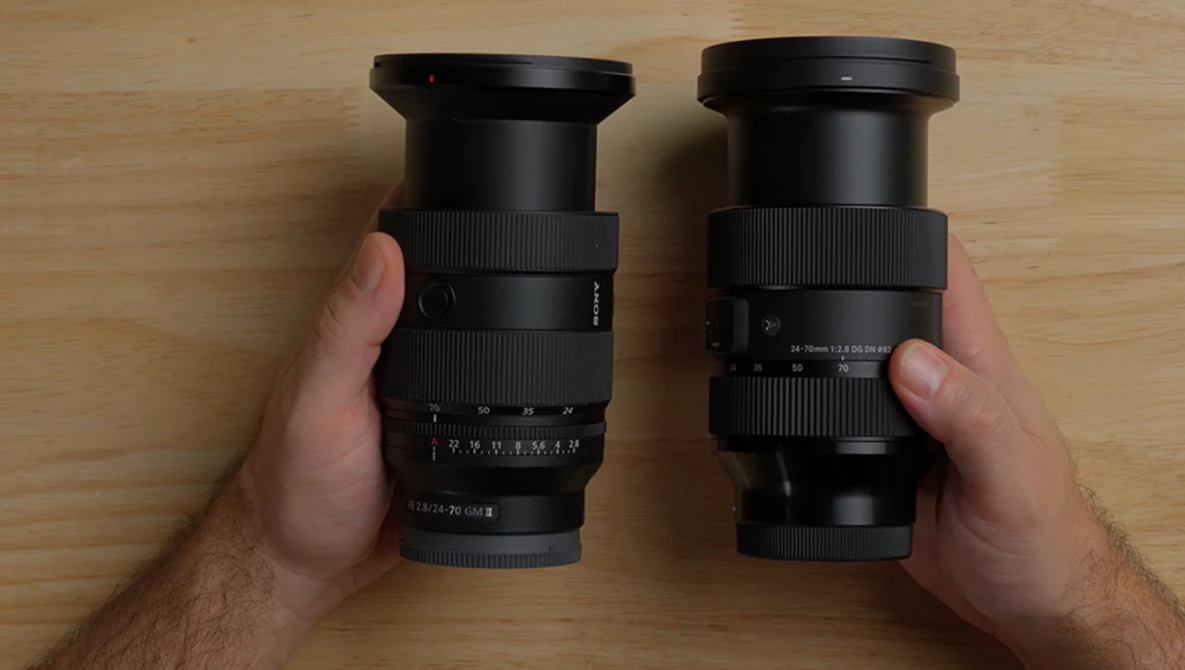 Two camera lenses held side-by-side in hands, showing barrel and focus ring details.