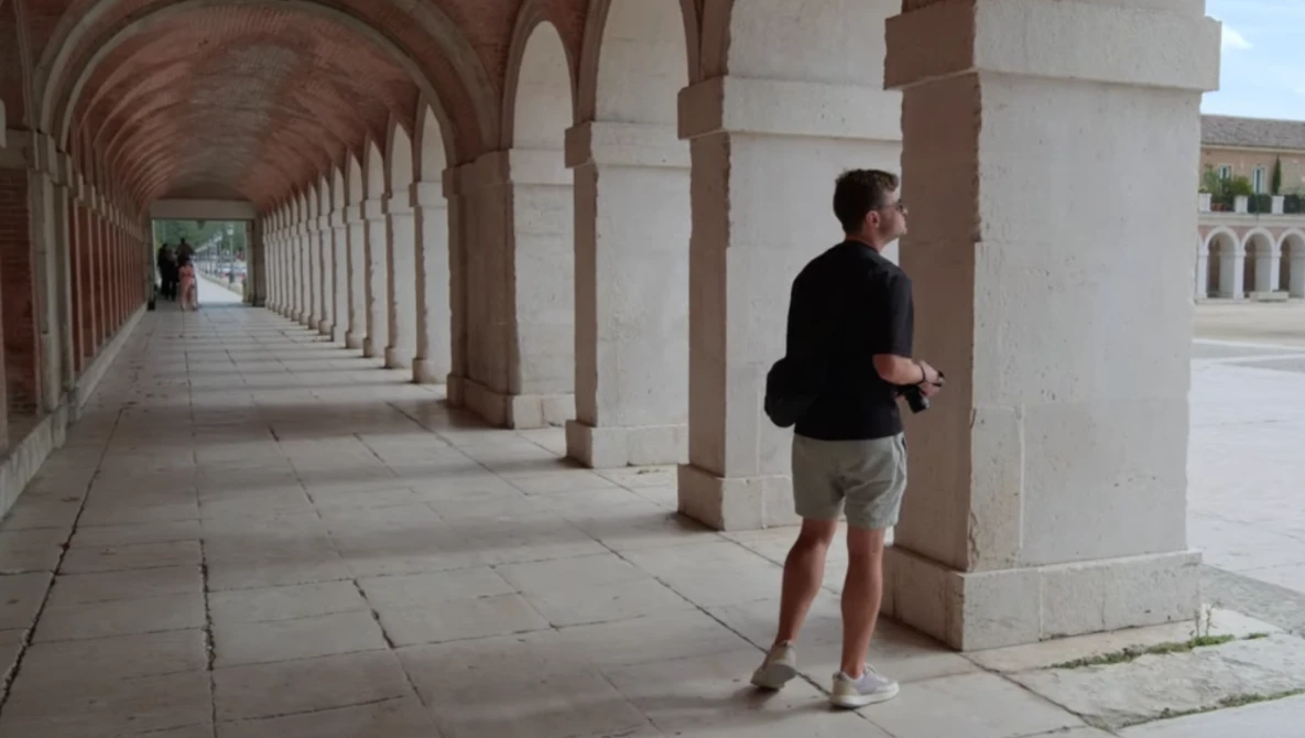 Runner jogging through a covered colonnade with repeating arches and columns.
