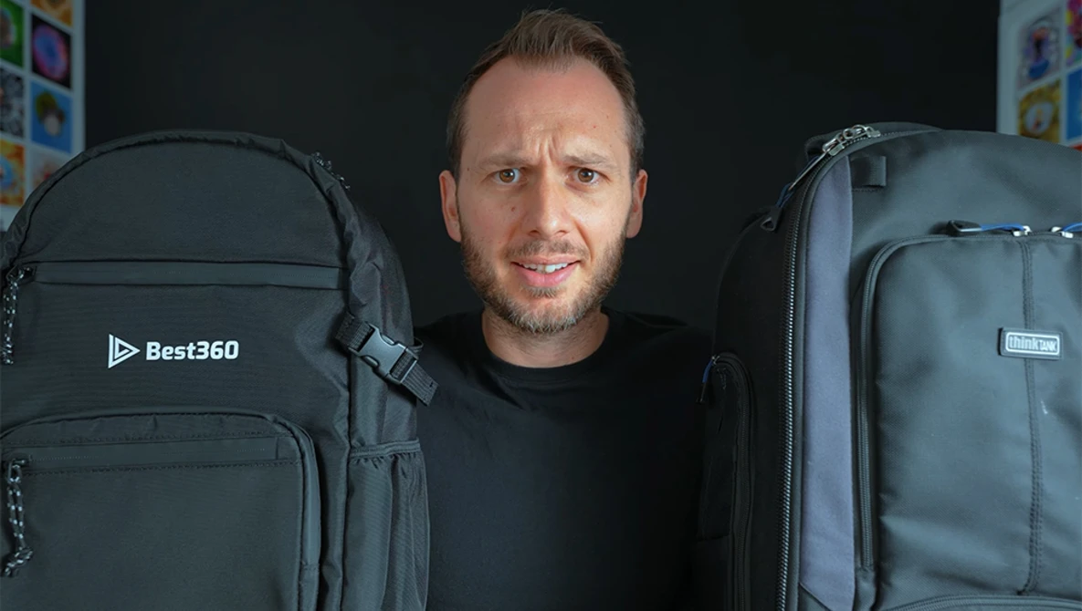 Man standing between two large black camera backpacks against a dark background.