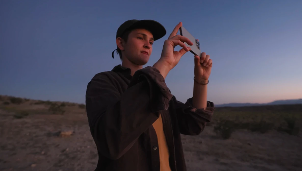 Photographer holding up fingers to frame a composition during golden hour in an arid landscape.