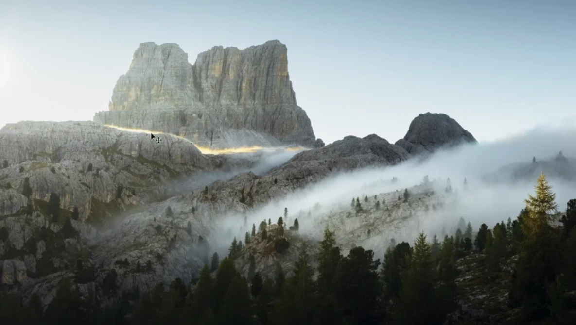 Dramatic mountain peak with columnar rock formations shrouded in rolling mist above a forested valley.