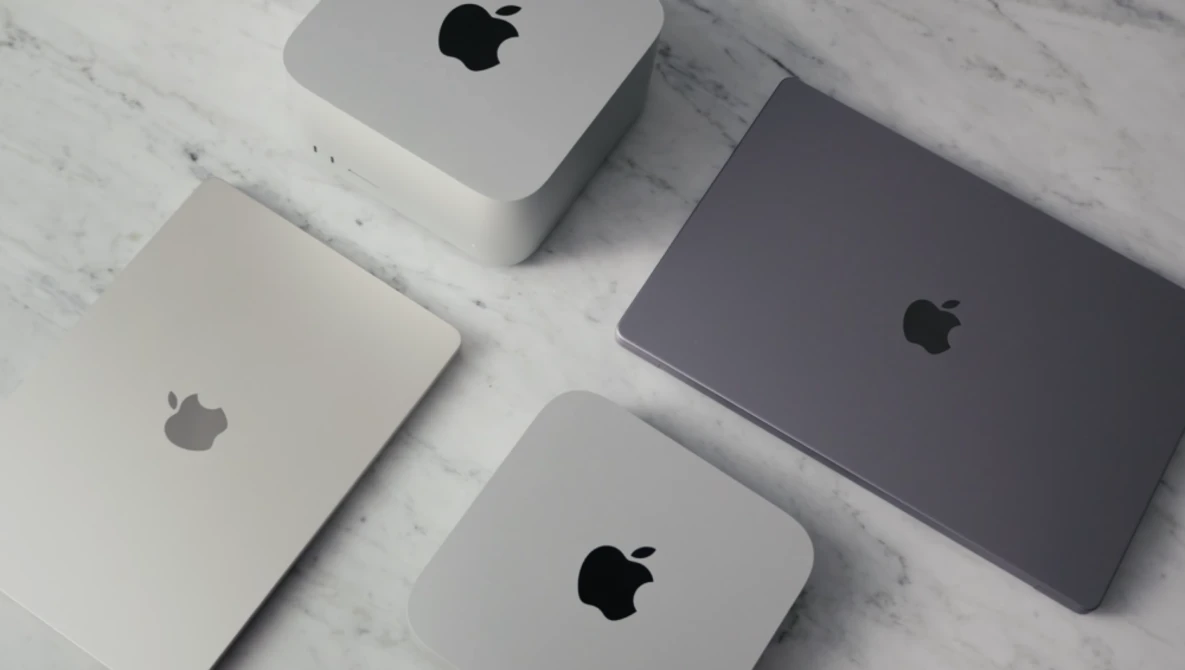Four Apple devices arranged on white marble surface in flat lay composition.