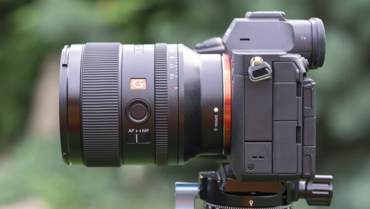 Sony mirrorless camera with wide-angle lens mounted on tripod head against blurred green background.