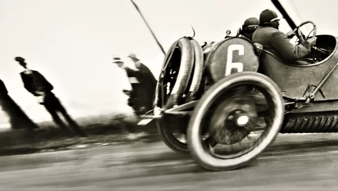 Vintage racing car number 6 captured in motion during early motorsport competition.