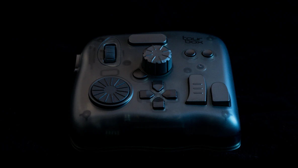 Gaming controller with analog stick, directional pad, and button layout displayed against dark background with blue rim lighting.