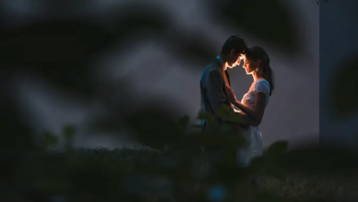 Couple embracing outdoors at dusk with warm backlighting creating a glowing silhouette effect.