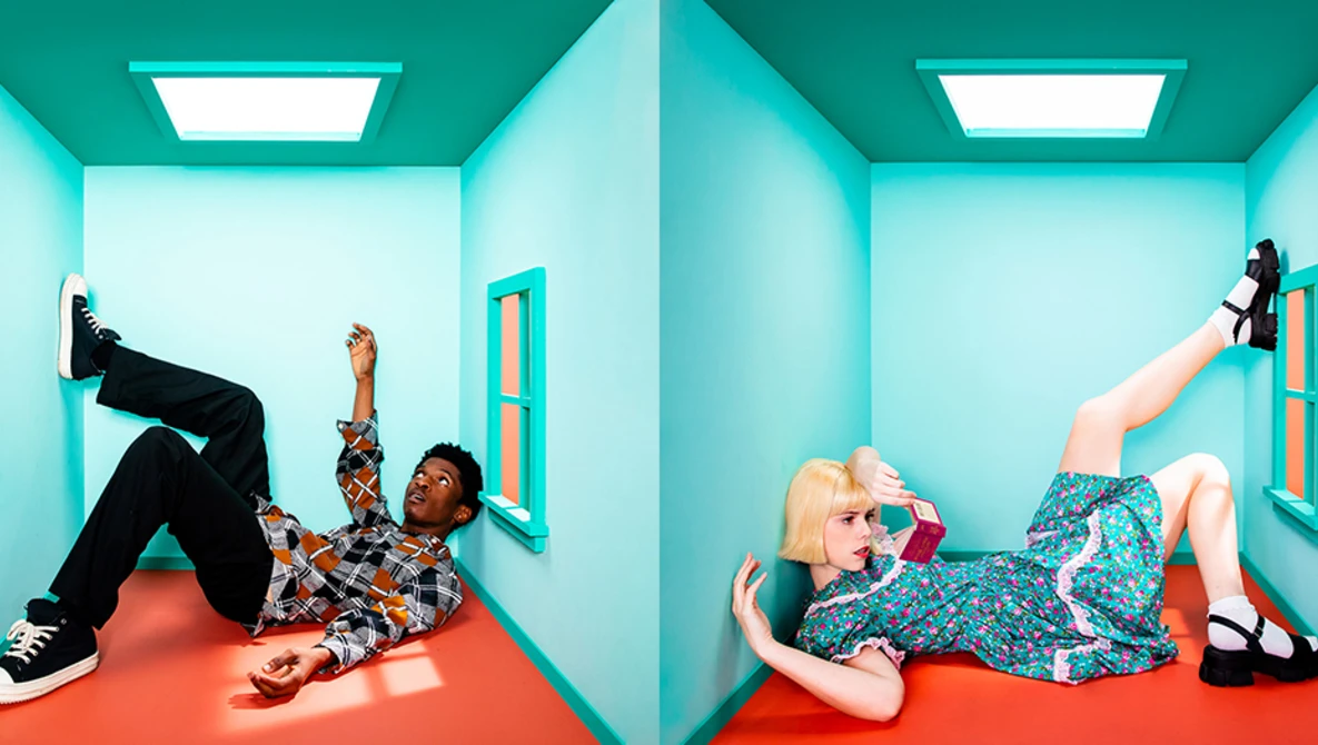 Two figures lying on bright red floors in symmetrical turquoise rooms with overhead lighting.