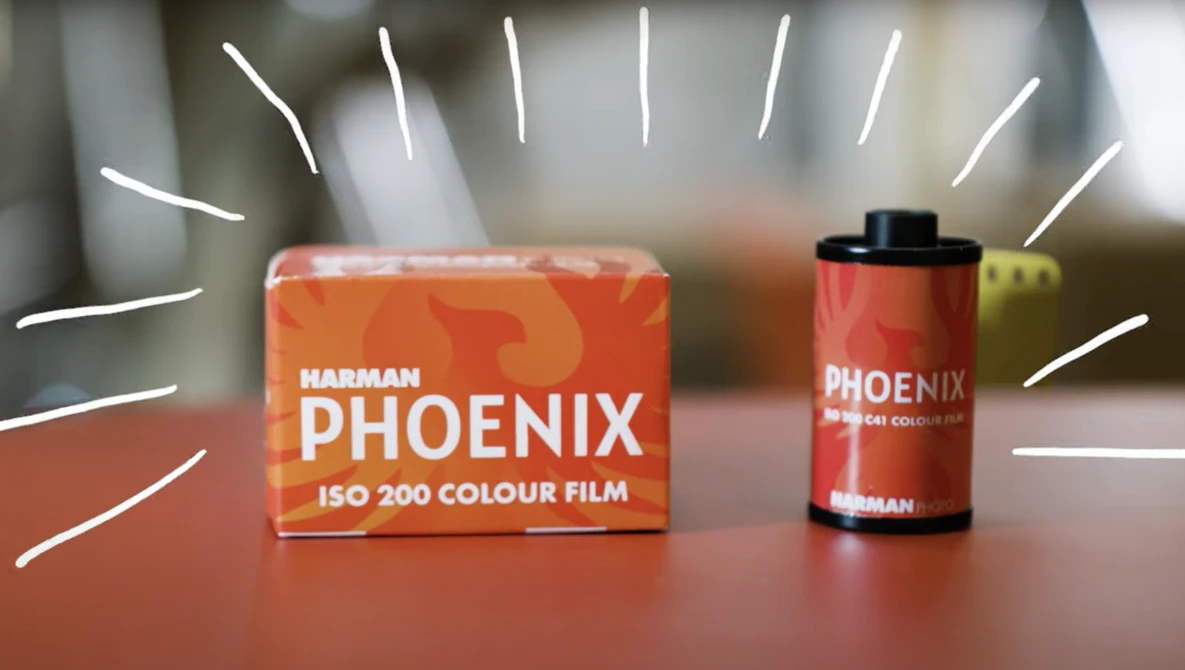 Harman Phoenix ISO 200 color film box and canister displayed on a surface with dramatic lighting.