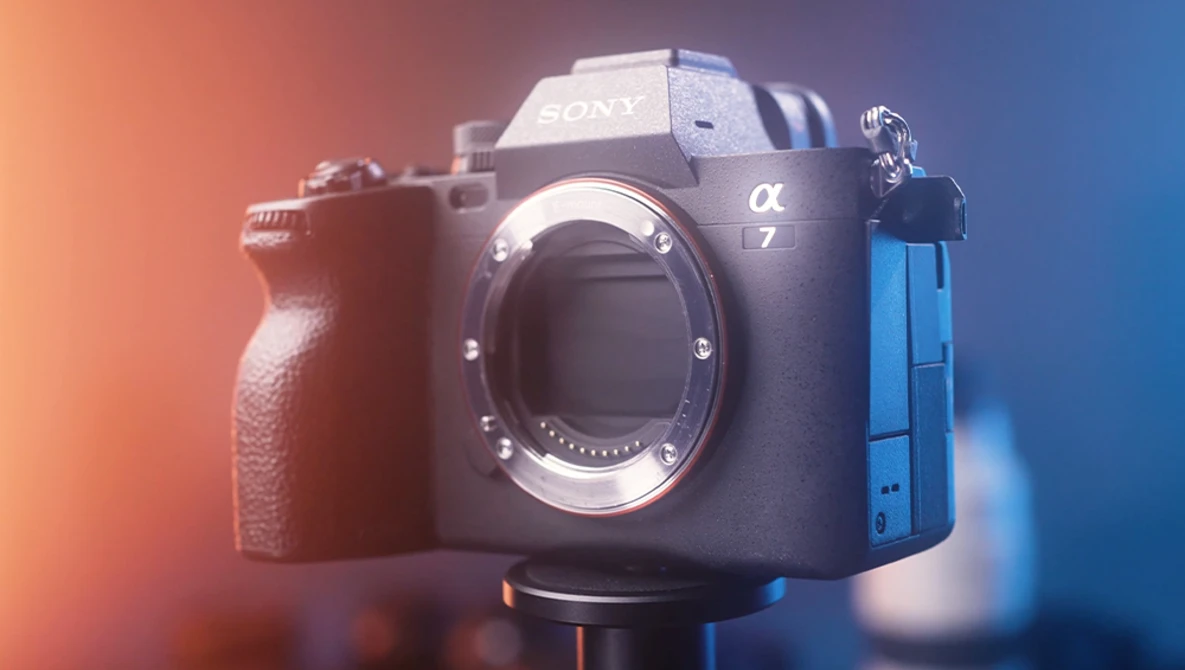 Sony a7 mirrorless camera body displayed against warm orange and cool blue gradient lighting.