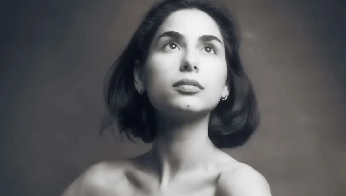 Black and white portrait of a woman with shoulder-length dark hair, looking upward with a contemplative expression.