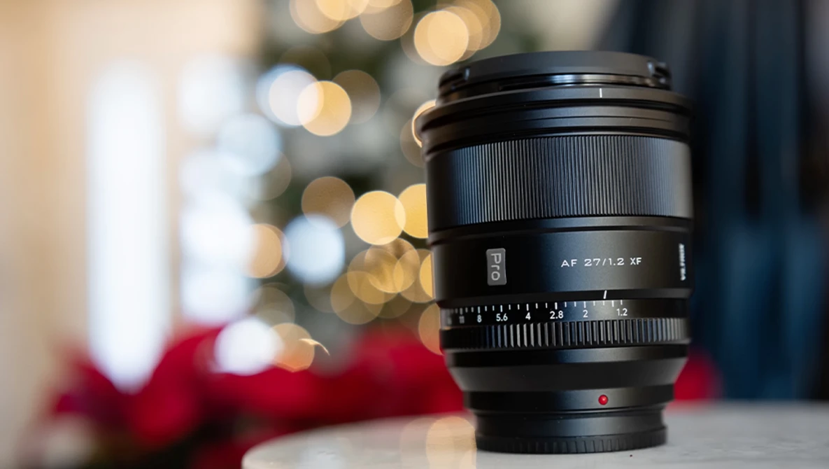 Sony AF 27/2.8 manual focus lens positioned in front of blurred holiday bokeh background.