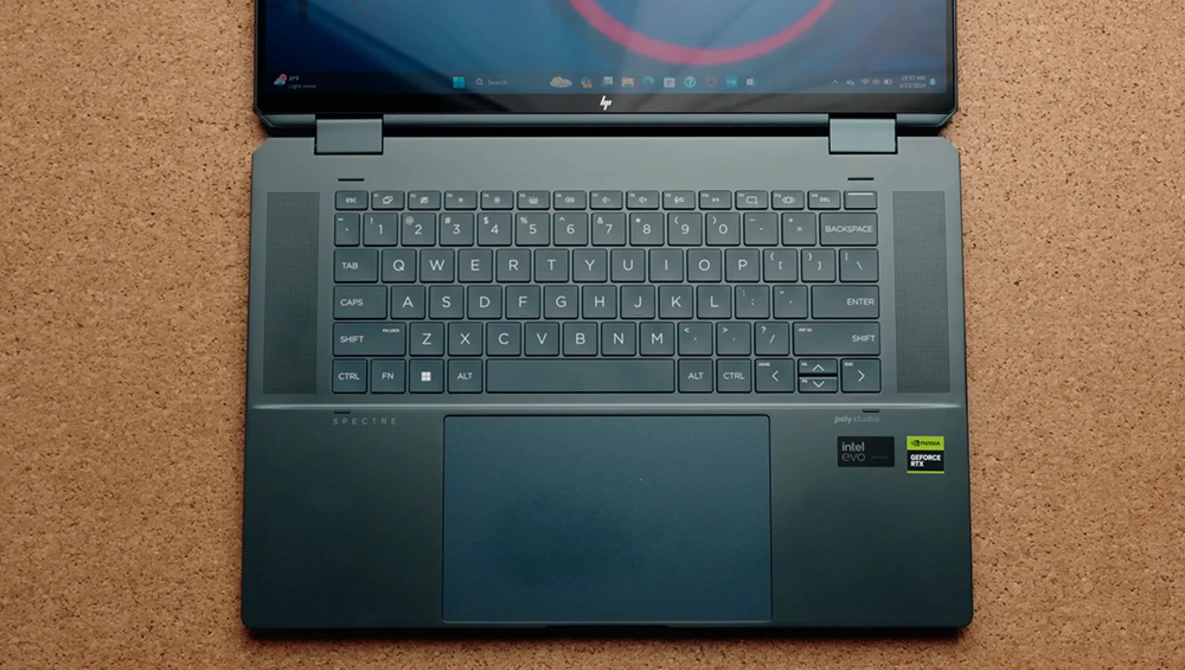 Laptop computer opened flat on cork surface showing desktop with circular design on screen.