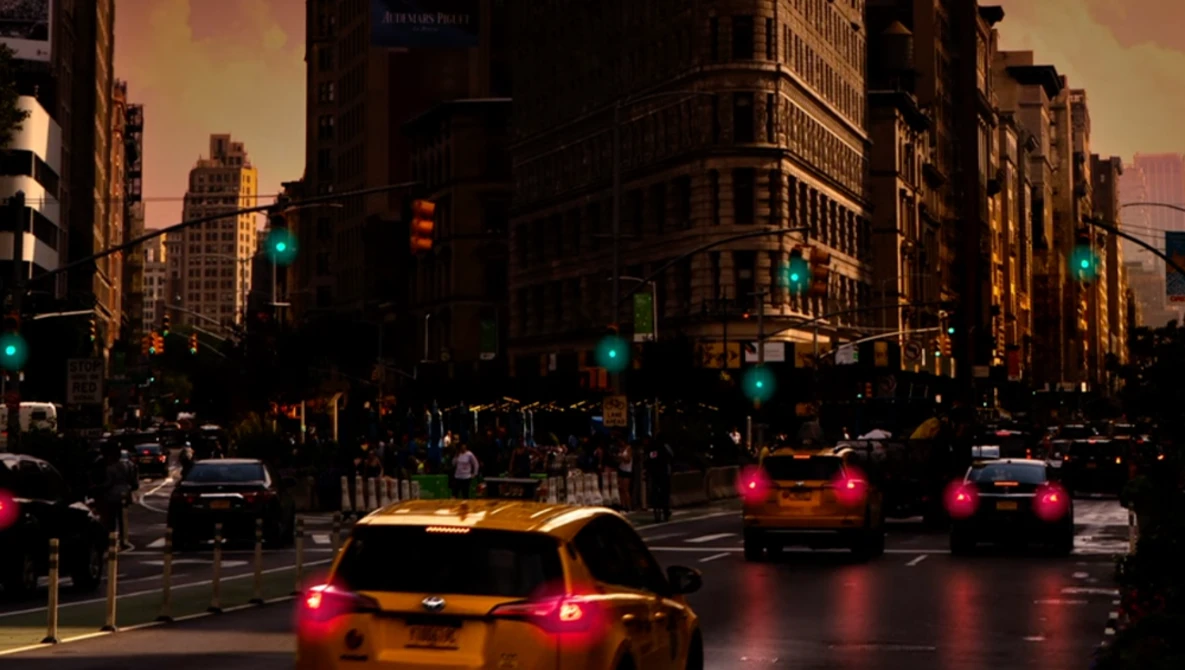 Yellow taxi cabs with illuminated taillights on a wet urban street at dusk, with traffic lights and tall buildings lining the road.