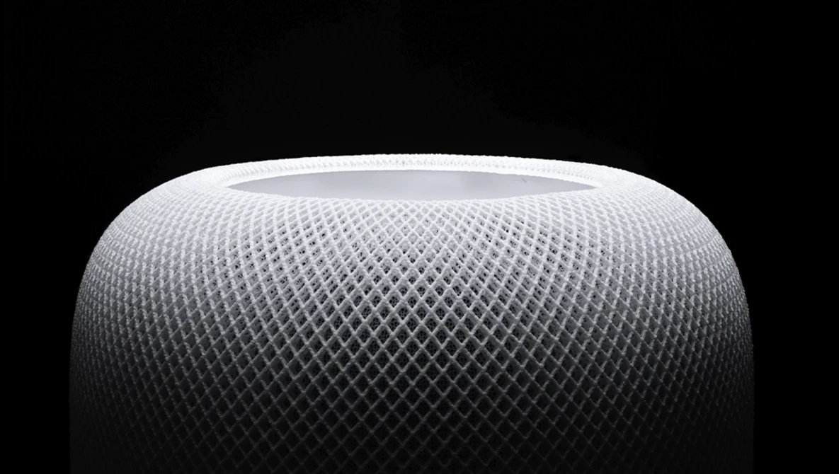 Close-up of a spherical speaker with a mesh fabric surface texture against a dark background.