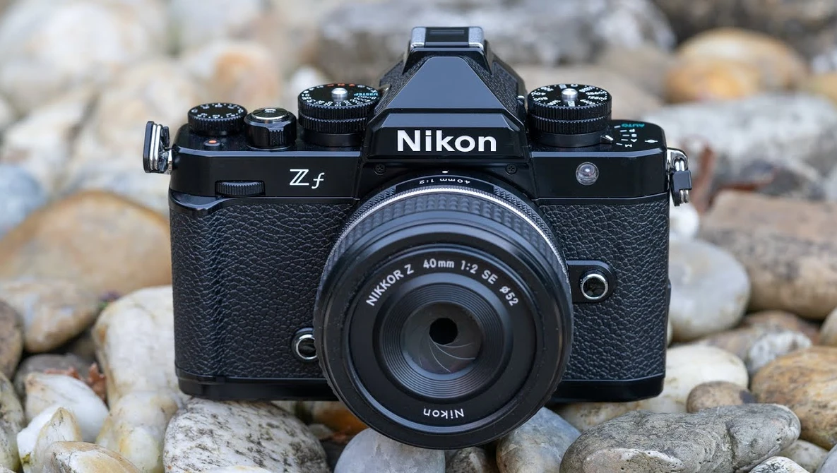 Nikon Z f mirrorless camera with 40mm f/2 lens on rocky ground backdrop.