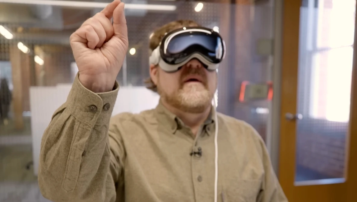 Man wearing VR headset with fist raised indoors.