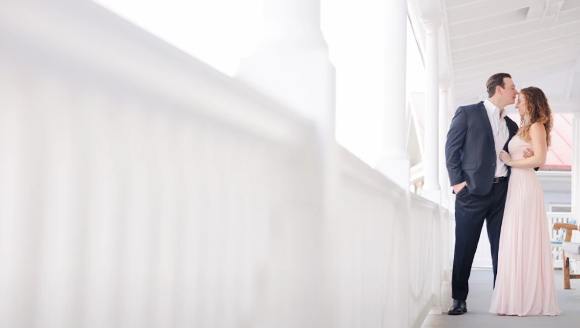 Couple in formal attire embracing in a bright, minimalist white interior space.