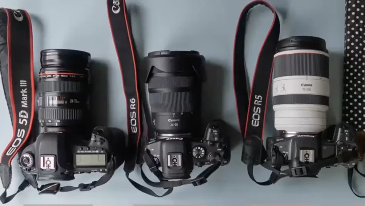 Three Canon EOS DSLR cameras with different lenses mounted, displayed side by side with red straps against a white background.