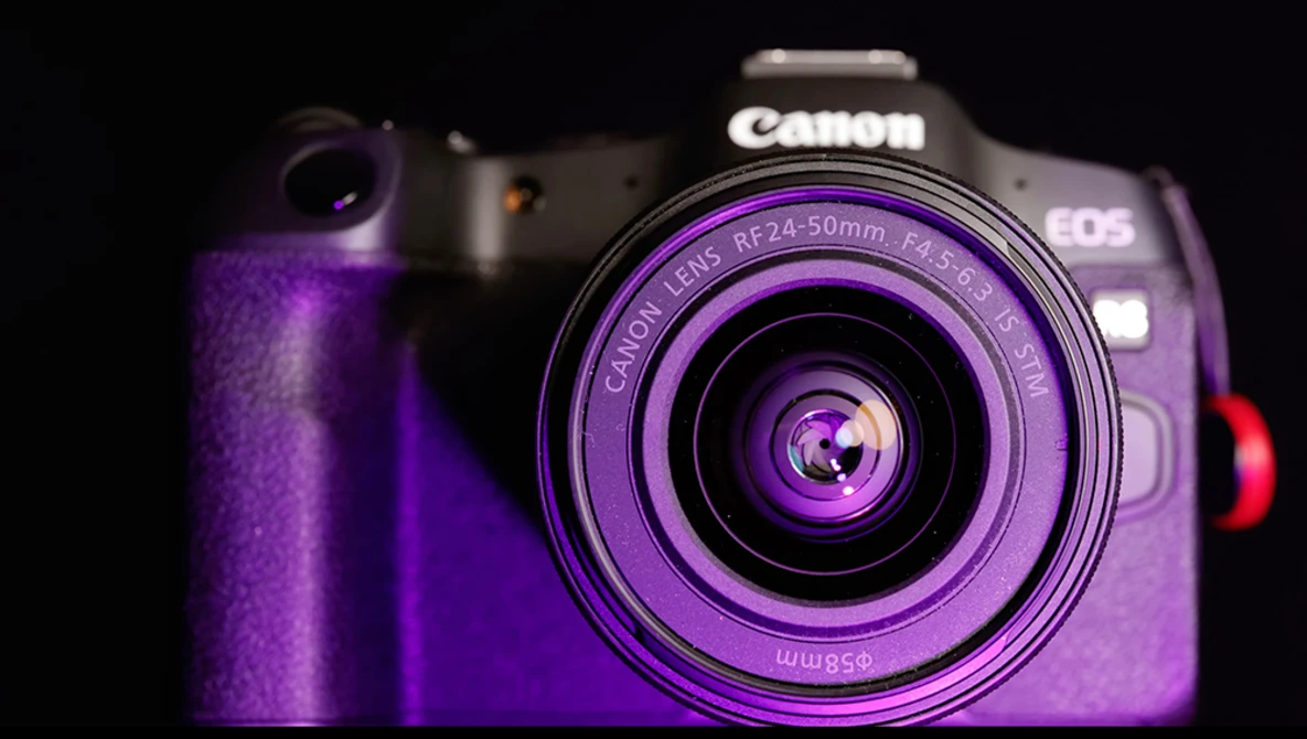 Canon EOS R5 mirrorless camera with RF 24-50mm lens bathed in purple studio lighting against a black background.