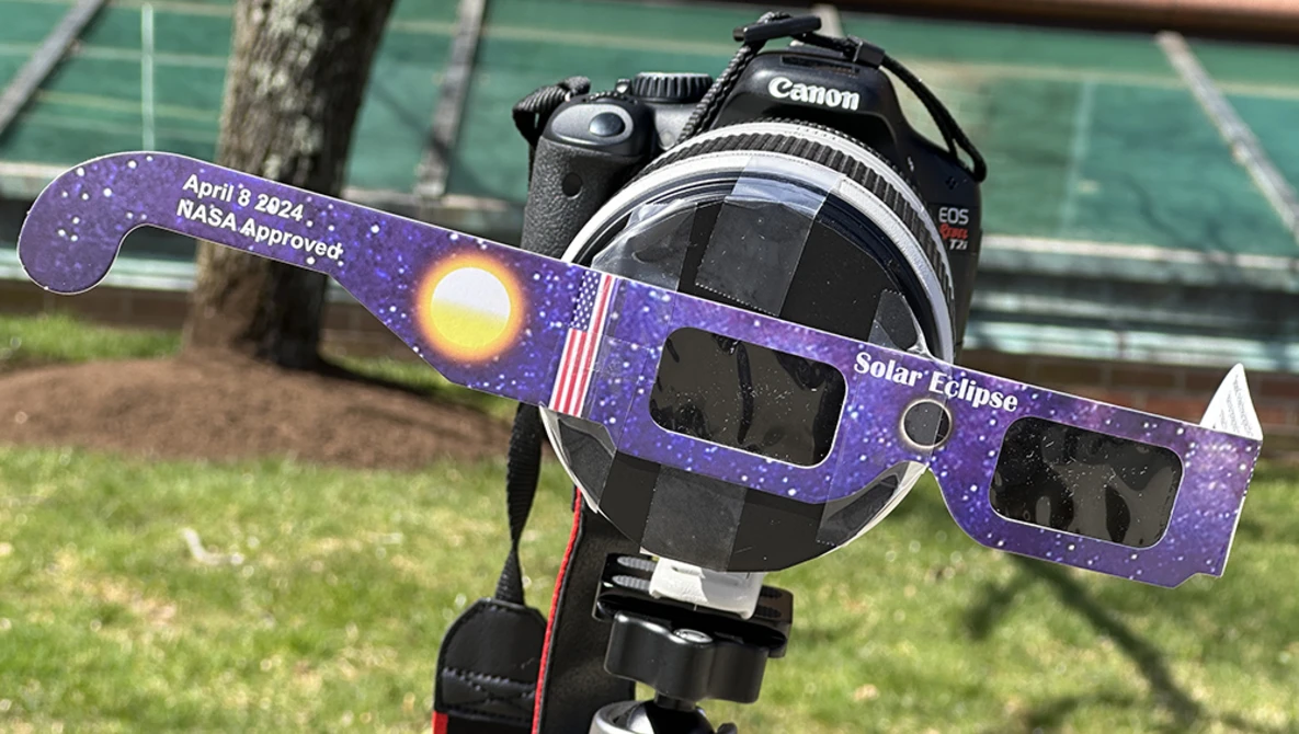 Canon DSLR camera with NASA-approved solar eclipse glasses mounted in front of the lens.