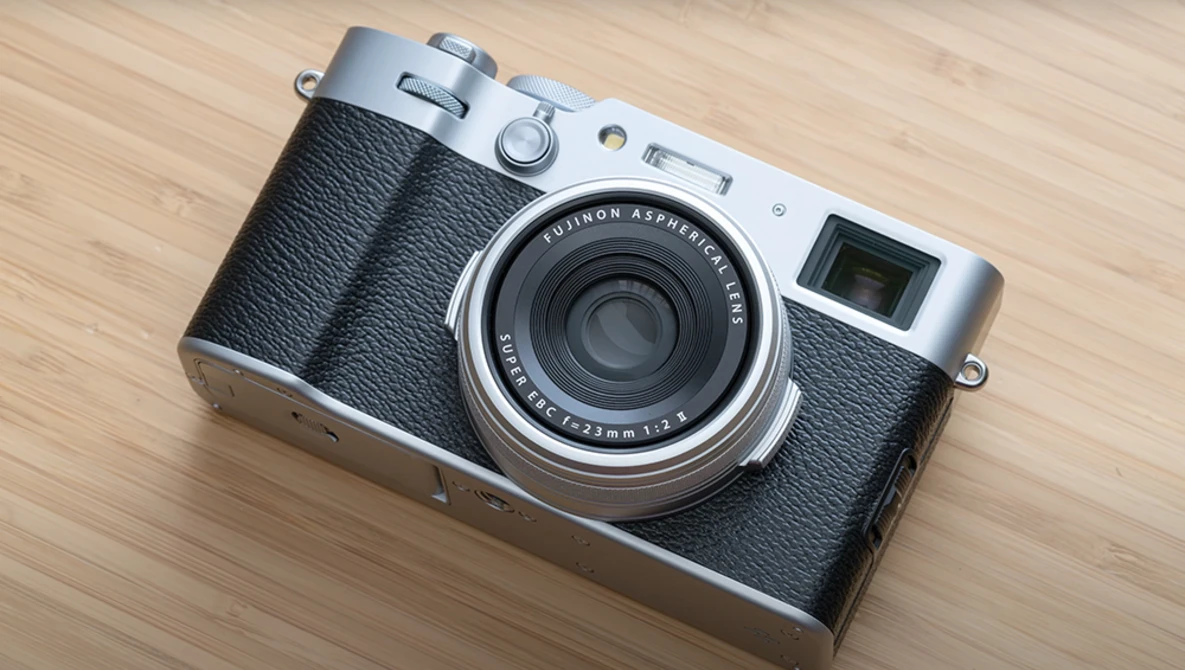 Rangefinder film camera with black leather body and silver top plate on wooden surface.